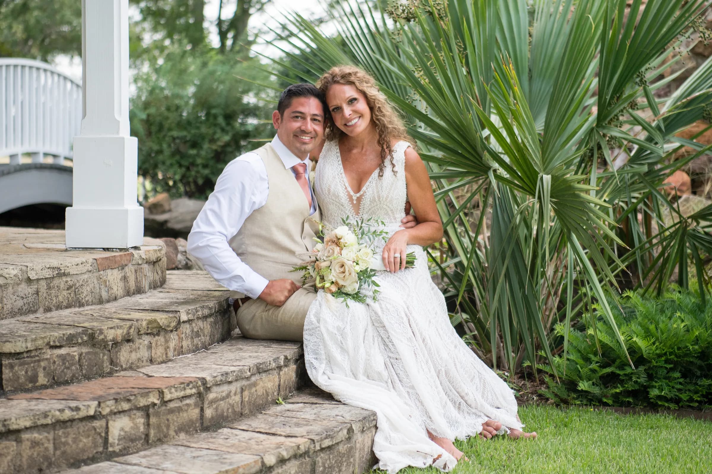 A couple seated on stone steps among the palms