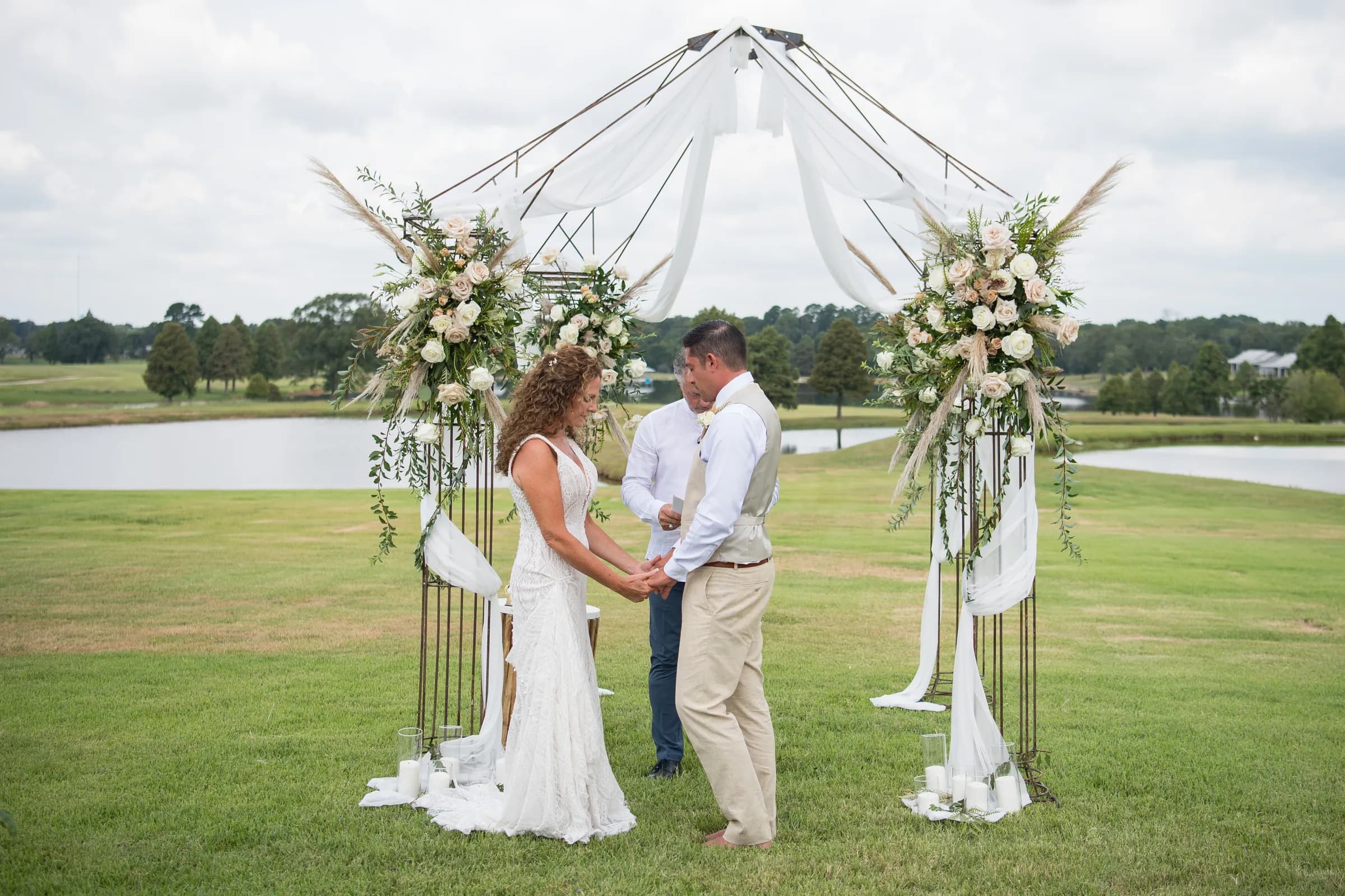 A couple exchanging vows under a floral arch